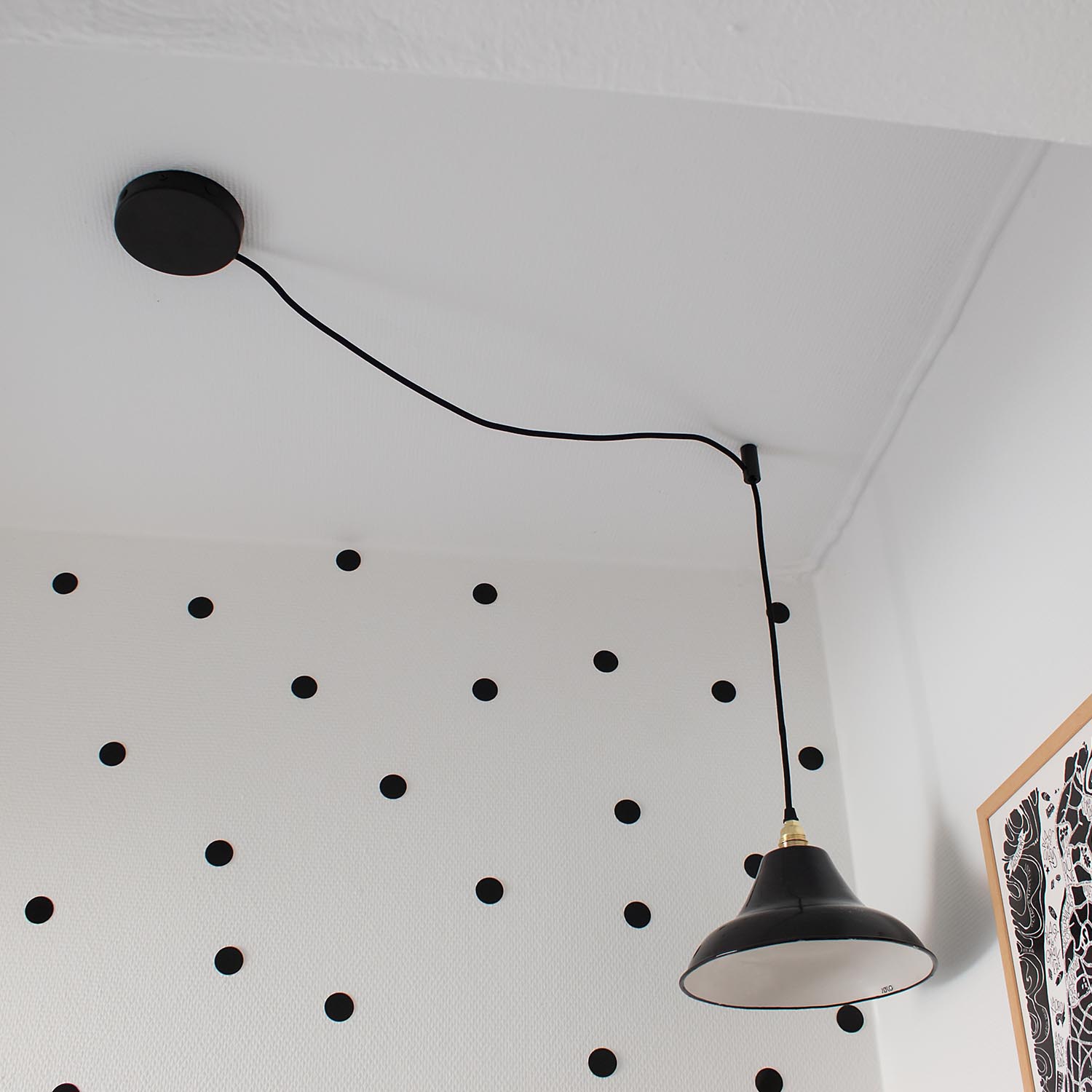 eine schwarze Lampe, die von der Decke hängt vor einer Wand mit Punktemuster